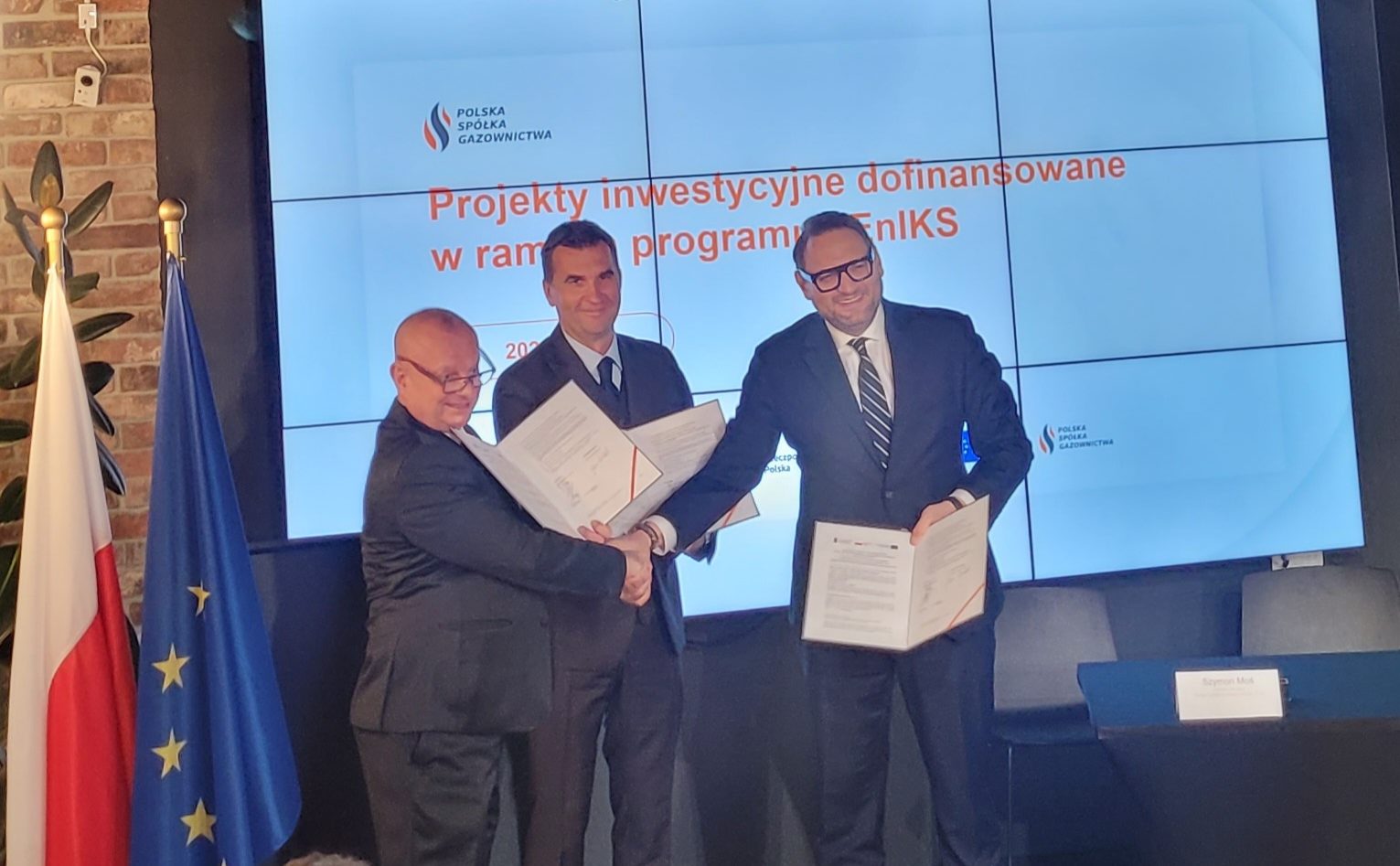 Na scenie trzy osoby: Jan Brożek, Dyrektor INiG-PIB oraz Arkadiusz Kazana i Szymon Paweł Moś, członkowie zarządu PSG sp. z o.o. podają sobie ręce w geście wzajemnej gratulacji podpisania umów.