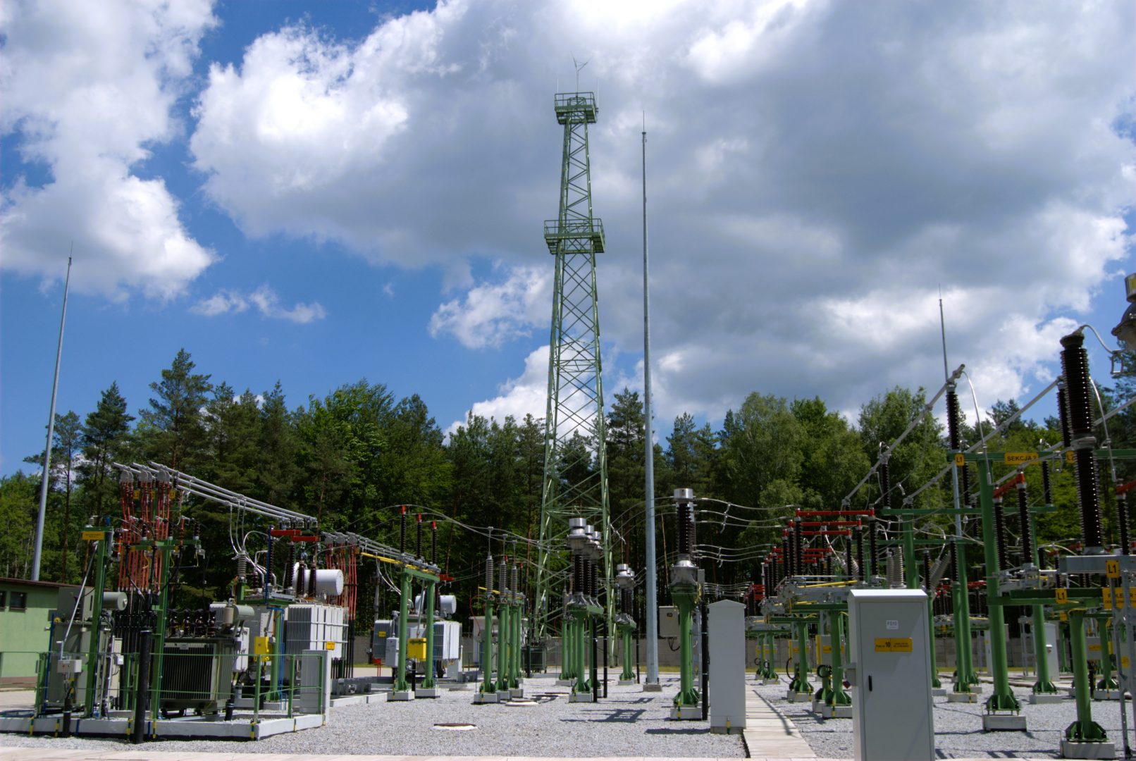Widok urządzeń elektroenergetycznych stacji GPZ Herby na tle lasu.